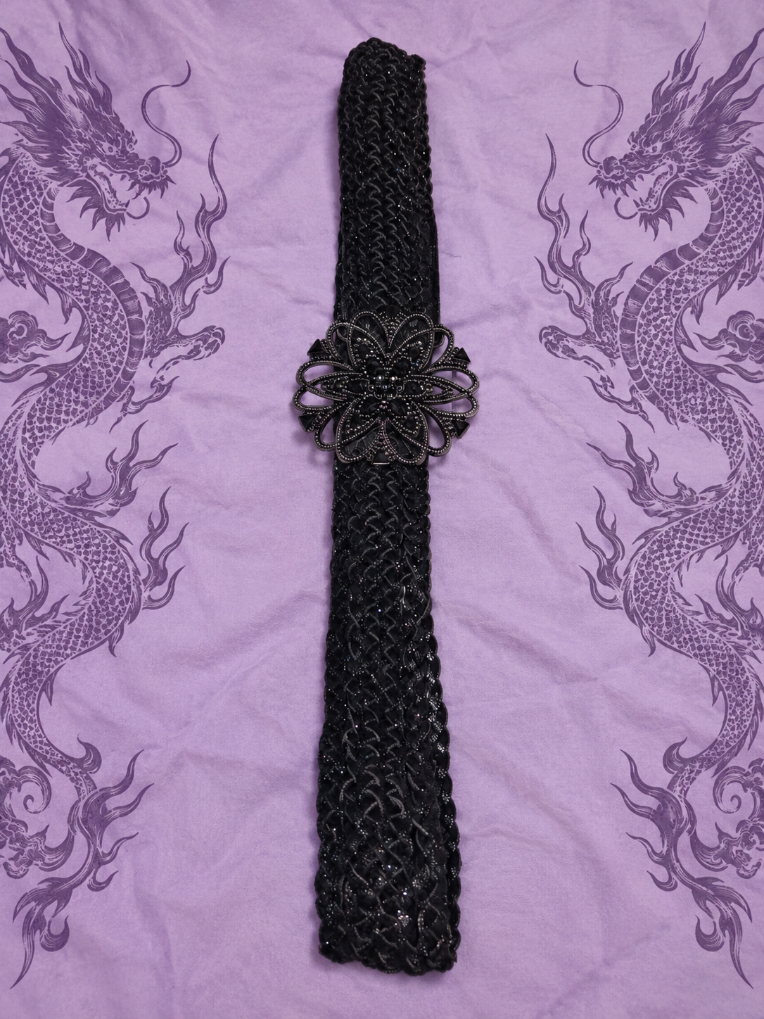 Cintura nera intrecciata con maxi fibbia floreale

Un accessorio dal carattere deciso, perfetto per completare outfit Y2K, gothic, boho e alternative.

Questa particolare cintura presenta una lavorazione intrecciata nera e una grande fibbia decorativa a f